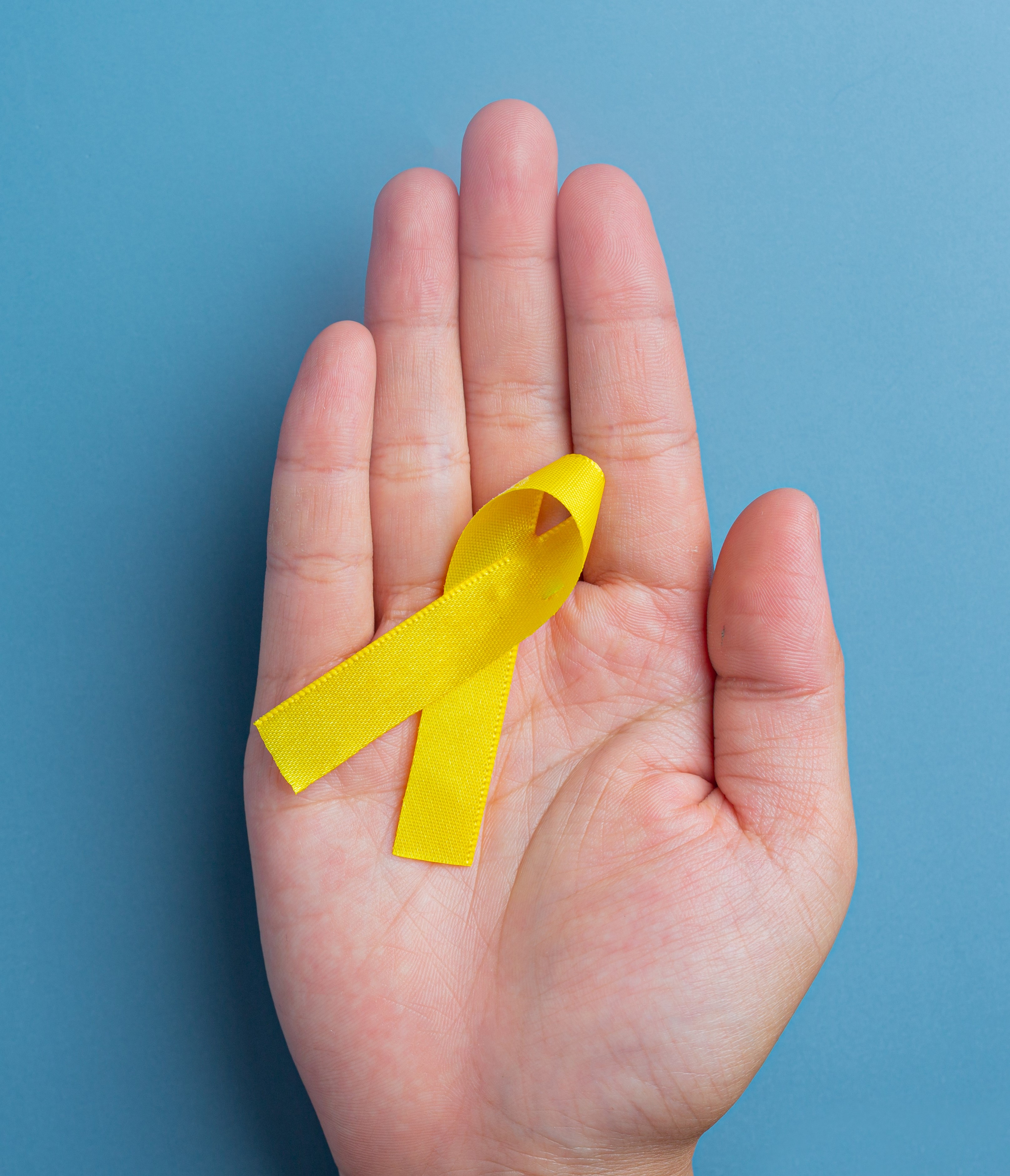 maos-segurando-uma-fita-amarela-simbolo-da-conscientizacao-do-cancer-suporte-medico-e-prevencao-com-mao-amiga-1